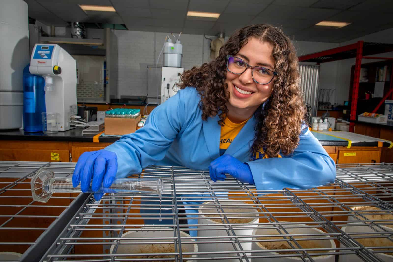 Microbiologist in lab handling petri dishes and scientific instruments for research.